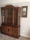 china cabinet flanked by a pair of prints