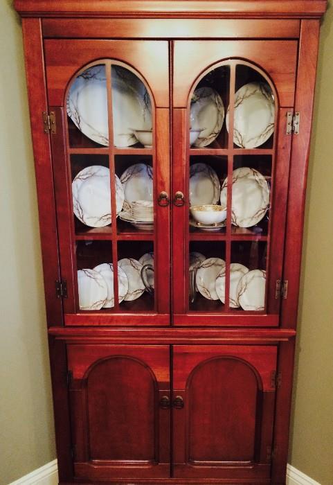 One of a matching pair of corner curio cabinets displaying eight-person place setting of Kent china