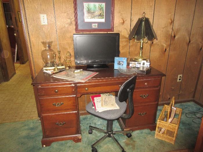 Cherry desk with kneehole, computer monitor and swivel desk chair.