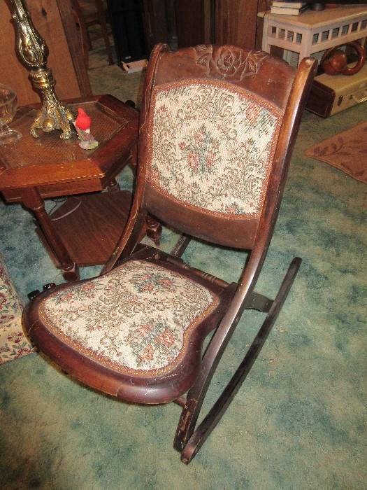 Upholstered seat & back, mahogany rocking chair with rose carved motif on back of chair.