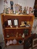 Small bookcase loaded with angel collections and small frames.