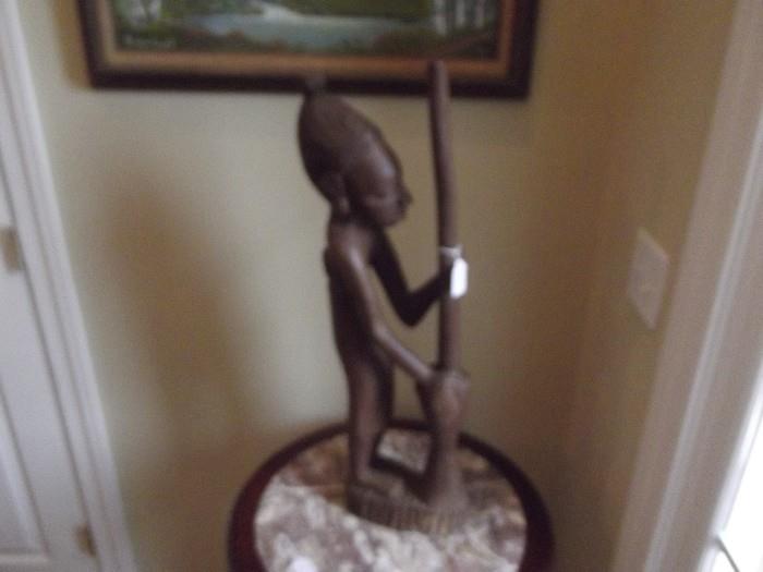 Wooden statue of woman with pounding/grinding pedestal .