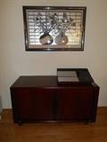 Living Room: HOUSE OF DENMARK credenza/stereo cabinet measures 48" wide x 26" tall x 20-l/2" deep. It has sliding doors to store electronics on one side and records or files on the other side. On top of the cabinet is a BANG & OLUFSEN BEOMASTER 6000; nearby are a DENON CD player and a DENON dual cassette player. Also shown is a 1970s-1980s reverse painted 3-D piece of art.