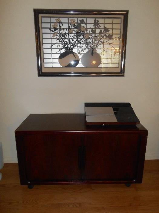 Living Room:  HOUSE OF DENMARK credenza/stereo cabinet measures 48" wide x 26" tall x 20-l/2" deep.  It has sliding doors to store electronics on one side and records or files on the other side.  On top of the cabinet is a BANG & OLUFSEN BEOMASTER 6000; nearby are a DENON CD player and a DENON dual cassette player.  Also shown is a 1970s-1980s reverse painted 3-D piece of art.  