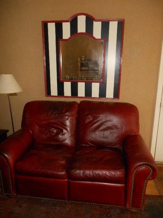 Family Room:  A 70" wide leather dual recliner with nail head trim is under a neat striped mirror which measures 43" wide x 44" tall.  To the left is a brass floor lamp.