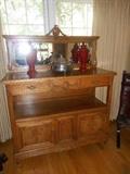 Family Room: An antique oak sideboard measures 51" wide x 64" tall to top of crest and 21" deep. The mirror section comes off for easy transport. There are two drawers on top and two doors on the bottom. It has been completely restored. Also shown are two urns and a silver-plate casserole.