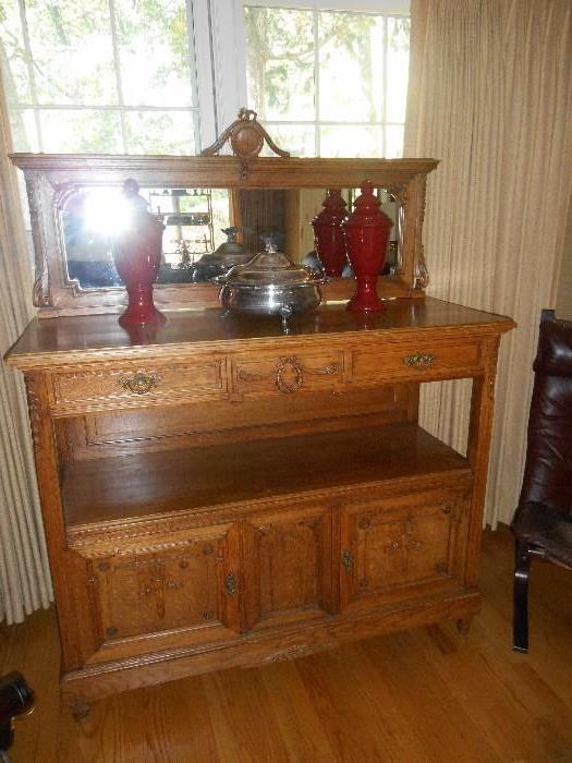 Family Room: An antique oak sideboard measures 51" wide x 64" tall to top of crest and 21" deep.  The mirror section comes off for easy transport.  There are two drawers on top and two doors on the bottom.  It has been completely restored.  Also shown are two urns and a silver-plate casserole.