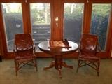 Lower Level: Two rattan/leather chairs flank a round pedestal table. The table measures 44" round and includes one 18" leaf, for a total of 62" x 44" when it becomes oval. On top is a chess game and wooden chess pieces.