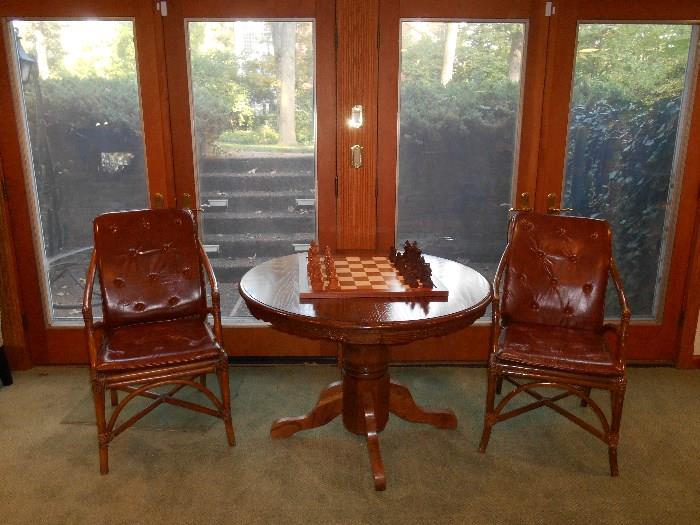 Lower Level:  Two rattan/leather chairs flank a round pedestal table.  The table measures 44" round and includes one 18" leaf, for a total of 62" x 44" when it becomes oval.  On top is a chess game and wooden chess pieces.