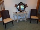 Lower Level: Two brand NEW woven chairs with neutral cushions (recently purchased at DeBasio for $375 each) flank a painted carved console. On the console is a black frame quatrefoil mirror (30" x 30")and two lamps with leopard pattern shades.