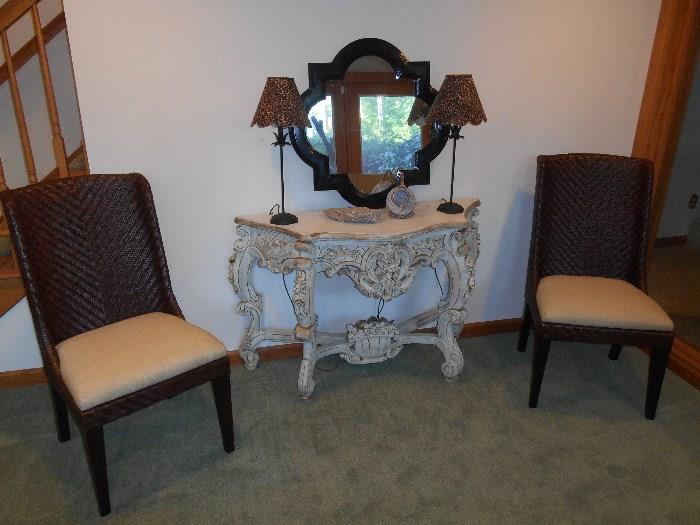 Lower Level:  Two brand NEW woven chairs with neutral cushions (recently  purchased at DeBasio for $375 each) flank a painted carved console.  On the console is a black frame quatrefoil mirror (30" x 30")and two lamps with leopard pattern shades.  