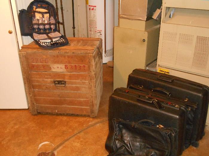 Lower Level: An old wooden crate; luggage.  A similar smaller crate is nearby as are shelving units, L.L. Bean cedar/canvas hanging wardrobes, dust mops, gallons of paints, and satchels.