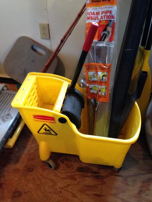 Yellow mop bucket with ringer, boxes of cleaners, solvents, paints, etc.