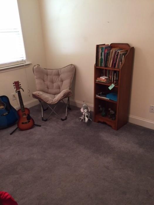 Guitar, bookcase, and casual chair in boy's room.
