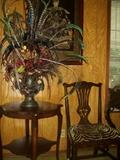 Side table, dining room chair, feather arrangement and artwork.