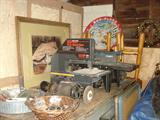 Bench top band saw, and router and router table. Cast iron scroll saw. Bench grinder. Chalk cat picture. Old snow saucers. In garage.