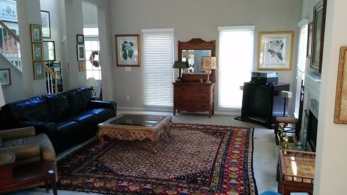 Overview of the living room. Nice Persian rug, measures 9' 6" x 11' 6", smoked & beveled glass-topped wooden coffee table, leather couch, oak dresser/mirror, petite mahogany TV/bar, framed/matted magnolia art.