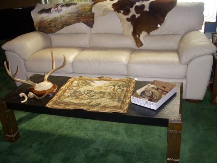 Leather sofa (background) with fur, Foreground is a coffee table with antlers, a tapestry and a stereoscope with cards