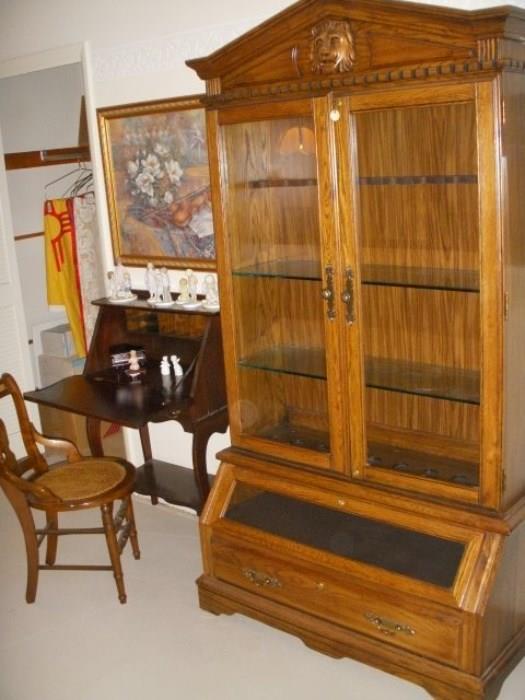Gun cabinet retro-fitted with glass shelves, but can be reverted to cabinet.  The doors do have a lock on them.  To the left is a slant-front writing desk