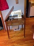 Antique sewing machine with self storing sewing table