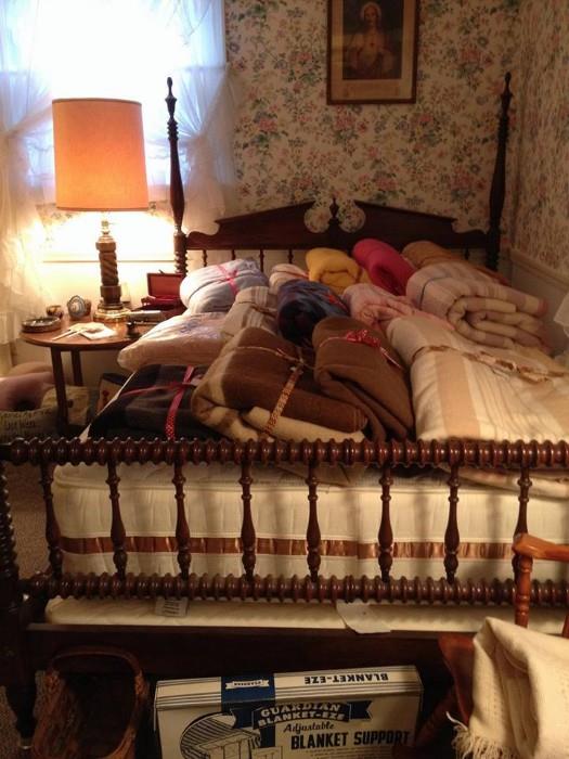 Vintage wood bed frame with spool turned head board and foot board. Blankets