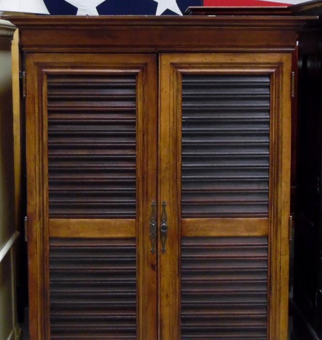 Louvered door entertainment/wardrobe with 7 drawers on bottom interior.