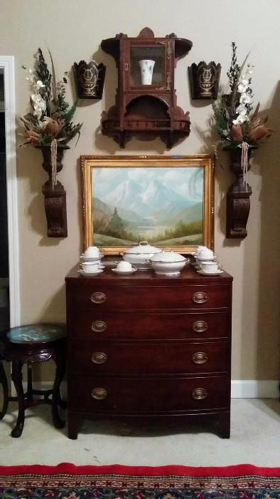 Very somber, yet fetching arrangement of 1940's mahogany 4-drawer (I can count) chest, Asian stool sample with cloisonné top, original artist signed oil on canvas, pair of faux wood (plaster) sconces, cast iron pots with really tacky 1980's Dynasty-ish (Deliverance?) floral stuff spewing out of them, anchored with a very nice Eastlake mahogany hanging cabinet, pair of toile wall vases and, that's finally about it in this pic.