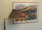 Brass floor lamp with swing-arm and brown & tan striped shade. Framed signed & numbered print of the Alaskan Railroad by Debra Dubac. 