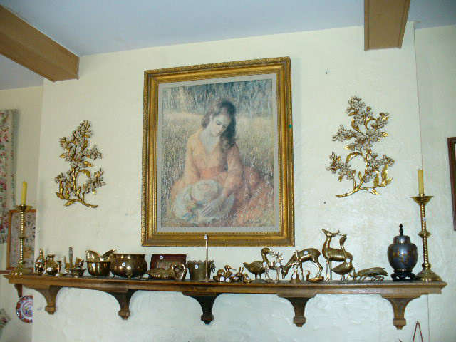 Mantel area with brass objects, wall decorations and framed portrait