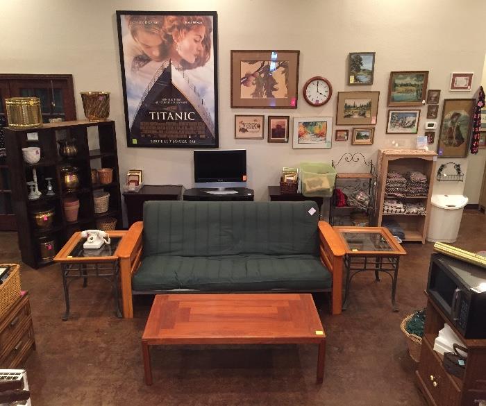 Wall full of art, teak coffee table, futon, glass and cherry end tables, flat screen TV and stand, planters.