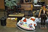 Various Antiques & vintage items. From England, USA, among others. Gossip bench, raggedy Ann rocking toy, Iron and brass candle sticks, statues, wicker, plants, bird cage, underwood typewriter, wine rack, and more