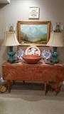 LOVE this antique heart pine, drop-leaf dining table, pair of vintage teal porcelain dragon lamps, large hand-turned pine bowl, vintage English charger, original, artist signed oil painting, on canvas, pair of crystal sconces from the old Biltmore Hotel, Polish lead crystal/silver plated jars, pine/embroidered footstool. 