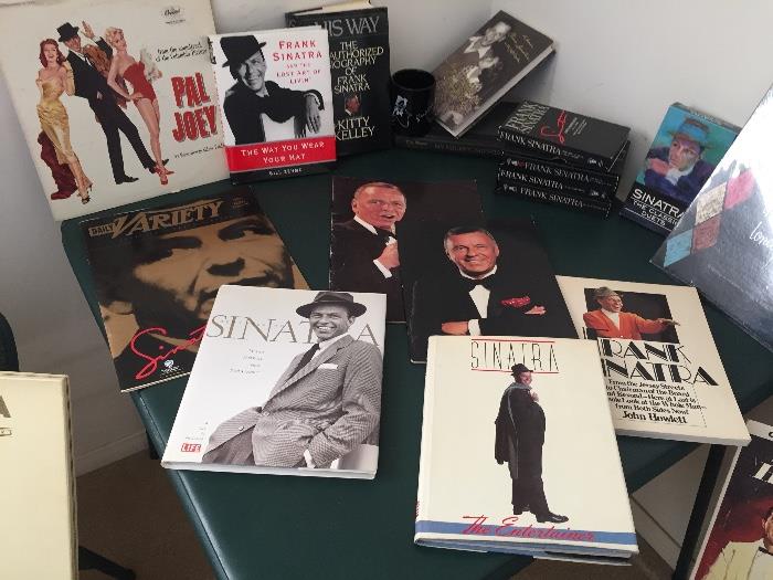 Collection of Frank Sinatra memorabilia. Books, albums, cassettes, programs, VHS tapes, CDs, watches (not shown), coffee cup, & wine glass.