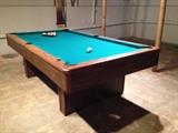 Pool table. Cues are on the wall in the background.