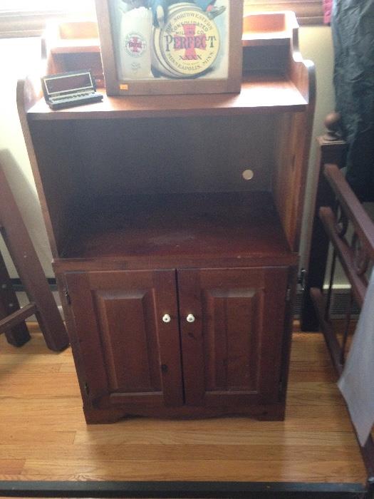 Cabinet of solid wood, could be used for microwave or tv. On top is a small  wall mounted cabinet with vintage advertising on door.