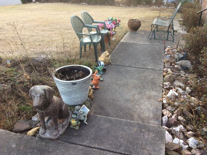 Statuary outside along with 2 molded plastic chairs and a metal glider