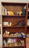 Another tall bookshelf with a few books, brass gingko leaf bookends, assorted office supplies, Speedball block printing supplies & a million binder clips.