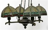 Lot#1009, BRADLEY & HUBBARD PATINATED METAL & GLASS FOUR-LIGHT HANGING FIXTURE/CHANDELIER, H 12", W 23",,A patinated metal hanging fixture having four hexagonal paneled shades with pierced brickwork and leaf motifs, backed by yellow slag, green and red glass; signed "B & H" encircled (see photo). Above measurement is only from the finial of a shade to the base.