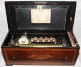 LOT#32  SWISS INLAID ROSEWOOD MUSIC BOX, H 10", L 28", D 13", Inlaid wood in musical instruments motif. Birds, bees and dragonflies adorn chimes;  Floral & leaf design. 10 1/2" H. x 28" L. x 13" D.