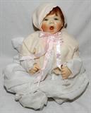 LOT#83  SHEILA MICHAEL WAX DOLL, 'ANNE CATE' C1993, H 16", seated position, having a wax head and hands, fixed blue eyes, hair lashes an open mouth, tongue, no teeth, cloth with dense pellet filled body, lace night gown with bonnet, sweater and booties.