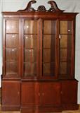 LOT#132  MAHOGANY BREAKFRONT, CIRCA 1940, H 88", L 60", D 17", Upper section features carved open pediment across the top with pierced leaf design above two central doors, with blown glass, flanked by single doors, also with blown glass, and having adjustable shelving.  The lower section has two central wood doors flanked by wood doors on each side and revealing single shelf cabinet space.