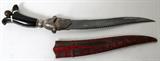 LOT#194  OMAN KHANJAR DAGGER, DAMASCUS, SILVER AND HORN 18TH C, L 11" SERRATED BLADE, having a primitive pattern Damascus double edge serrated re-curve 11" blade; engraved silver fuller, hilt and tang with slab and pinned horn; eared pommel with bone inlays and silver acorn finial; includes a red velvet and embroidered sheath.