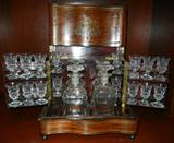 LOT#1030  FRENCH INLAID ROSEWOOD TANTALUS, 19TH C., H 11", W 12", FITTED WITH DECANTERS & CORDIALS, A rosewood serpentine-form tantalus with inlaid brass banding and embellishments at the top and front, opening to a set of 4 glass decanters, H.8", and 16 cordials.  Measures H.10 1/2" x 11 1/2" x 9".