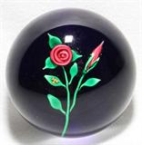 LOT#1187  CHARLES KAZIUN GLASS PAPERWEIGHT, DIA 2 1/4", Red rose stem on cobalt ground, bright green leaves accented by a gold bee, signed with a gold "K" on the reverse.