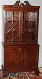 LOT#1230  CHIPPENDALE STYLE MAHOGANY CHINA CABINET, C. 1940, H 77", W 38", Two hinged fenestrated doors over cupboard base. D 19". Beautifully figured mahogany. Arched cornice, panel lower doors, bracket feet.