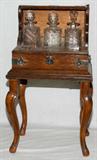LOT#1353  ENGLISH OAK TANTALUS, C. 1900, H 12", W 15", D 11", RAISED ON A STAND, H 27" OVERALL, The antique oak Tantalus fitted with three cut glass decanters, is flanked by handles, and raised on a contemporary stand, H.15".