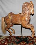 LOT#2056  M.C. ILLIONS CARVED WOOD CAROUSEL HORSE, H 51",  In a running position, angel motif in the back of saddle, studded with glass prisms, glass eyes, mounted on a brass pole.  Refinished in natural color wood.  Provenance: Boblo Island carousel