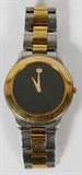 Lot# 34 MOVADO, STAINLESS STEEL BLACK WATCH, Black face gold tone hands, void of numerals, gilt dot at 12:00; goldtone bezel; stainless steel band with center gold tone links. 'Movado Since 1881' on back case cover;