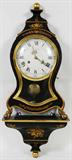 Lot# 37 LE CASTEL, FRENCH EBONY WALL CLOCK, WITH WALL BRACKET, H 20", W 11", D 4", Having gilt spherical finial above an face of Roman numerals for the hours and Arabic numerals for the minutes, gilt metal hands, two key wind, and inscribed: 'Fabr. Swisse' at bottom of face which is accessed through a full height contoured glass door with gilt painted door frame; The wall bracket base is 8" H. x 4 1/2" W. Ebony in color with gold tone floral and leaf designs. With pendulum and key.