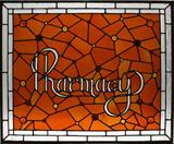 Lot# 70 HANGING STAIN GLASS WINDOW "PHARMACY" SIGN, H 30", W 36", Clear & orange. With frosted glass spelling 'Pharmacy' in the center of an orange field of irregular shaped glass pieces. Diffused and beveled glass narrow rectangular panels at the edges.